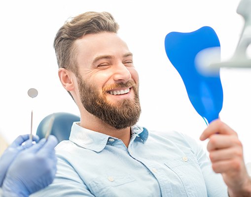 A man looking at his smile makeover results in a mirror