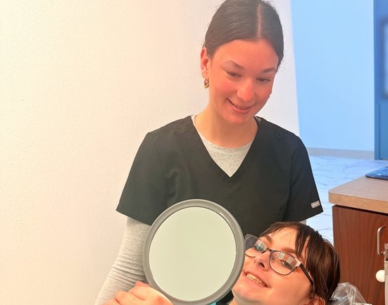 Highland Oak Dental team member smiling with a hand mirror in the dental chair in Frisco