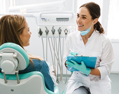 Dentist smiling while taking notes on clipboard