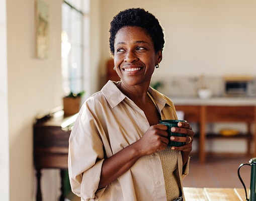 Woman smiling while enjoying cup of tea at home