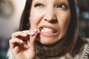Woman using toothpick on teeth.