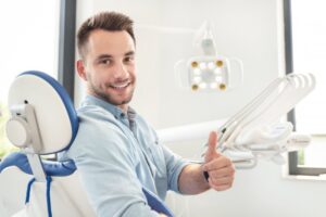 Man smiling and holding thumbs up at dentist