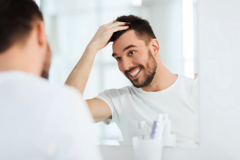 Patient smiling in mirror after teeth whitening